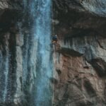 person in blue jacket climbing on rocky mountain during daytime